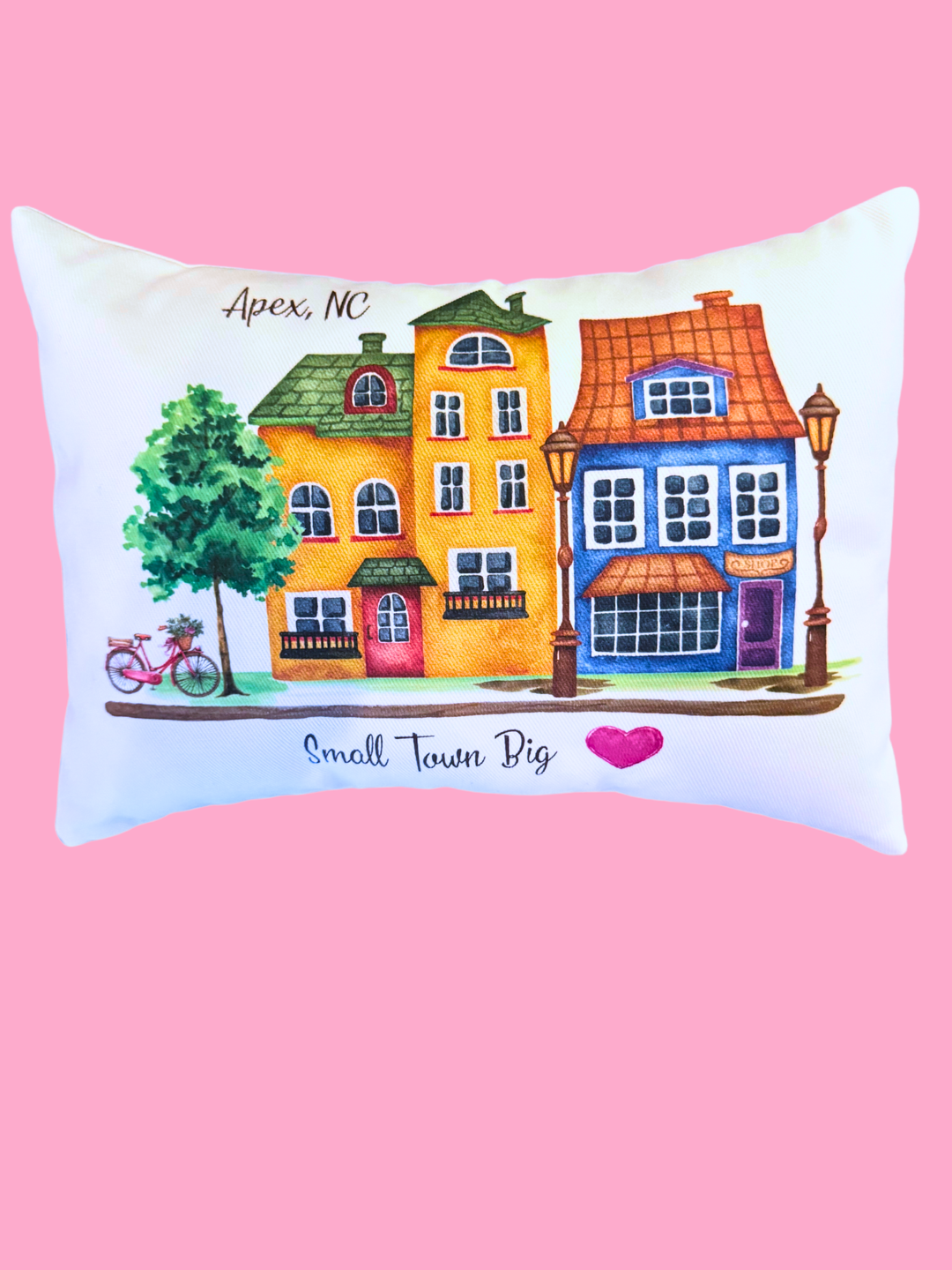 Decorative pillow with colorful houses and bicycle on a pink background