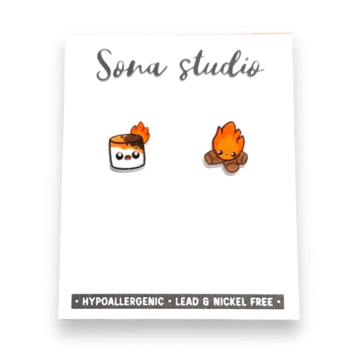 Two small earrings resembling a roll of sushi and a flame on a white card with 'Sona Studio' branding.