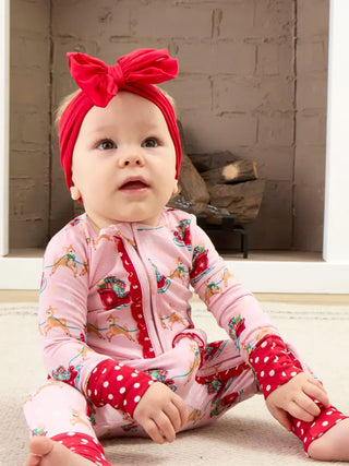 baby wearing pink onesie with red polka dot ruffle trim and reindeer with sleigh pattern