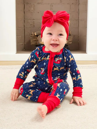 baby wearing navy blue and red onesie with reindeer, snow, and sleigh pattern