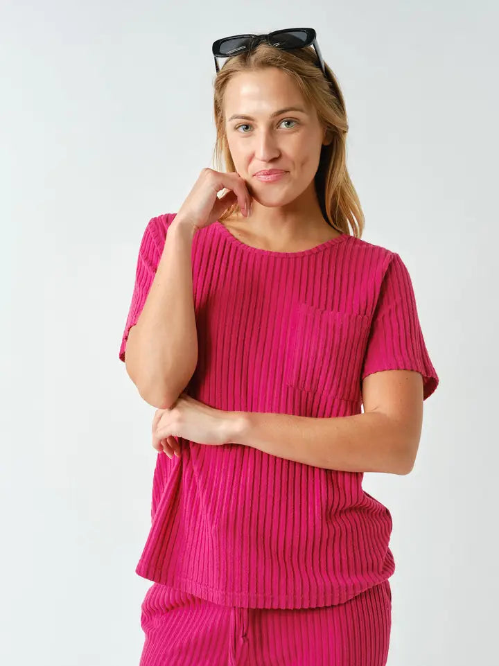 Woman wearing a pink ribbed top and pants on a white background
