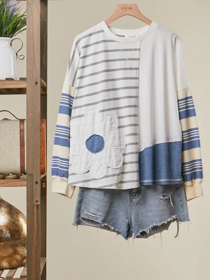 Striped cardigan with a pocket and denim shorts on a wooden hanger against a neutral background.
