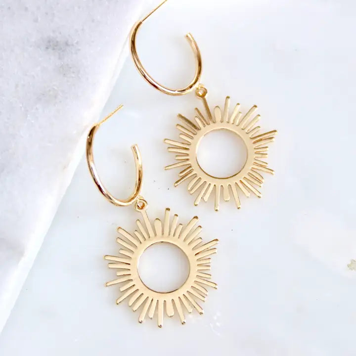 Gold hoop earrings with sunburst designs on a light background