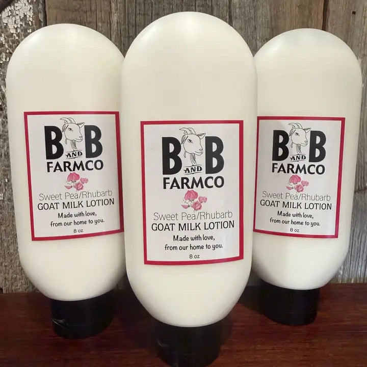 Three bottles of B&amp;B Farmco goat milk lotion on a wooden surface with a rustic background.