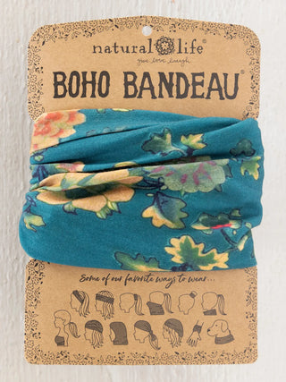 A folded blue fabric headband with a multicolor floral print, displayed on its original kraft paper packaging card labeled 'natural life BOHO BANDEAU'.