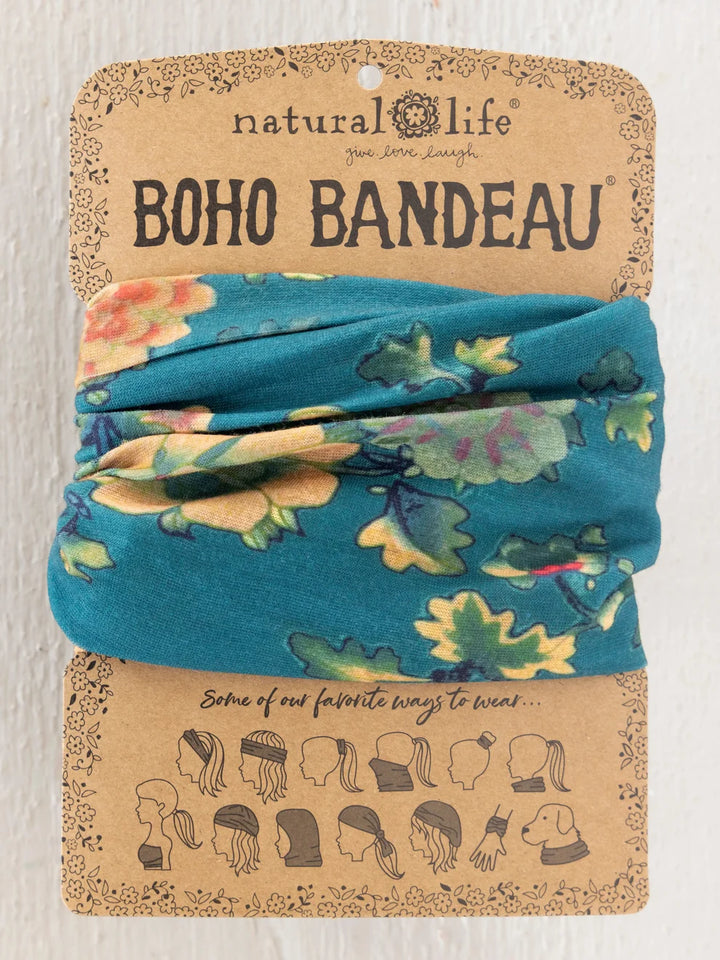 A folded blue fabric headband with a multicolor floral print, displayed on its original kraft paper packaging card labeled &