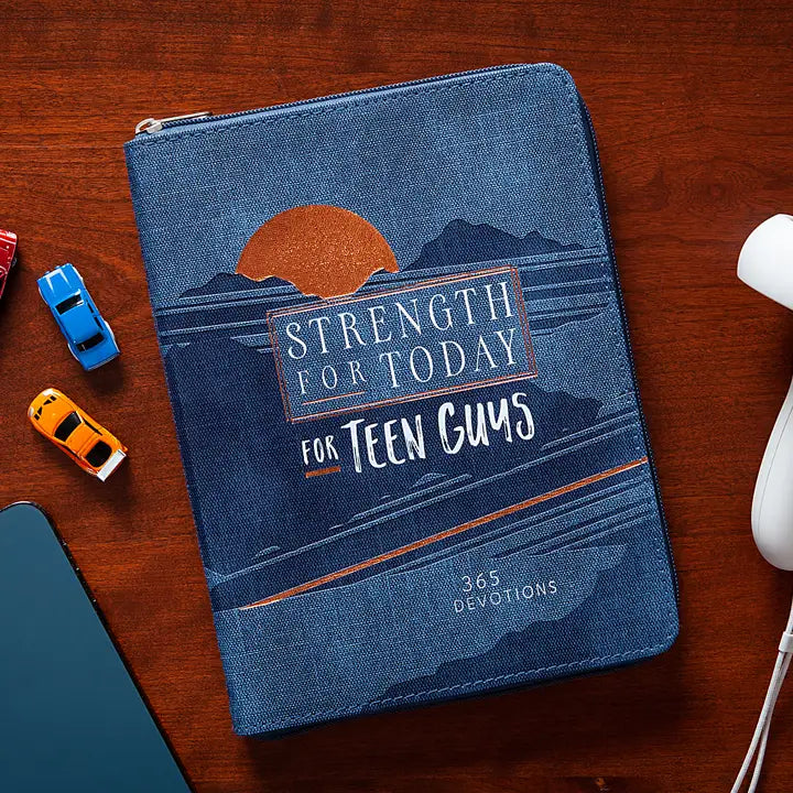 Blue book titled 'Strength for Today for Teen Guys' on a wooden surface with toy cars.