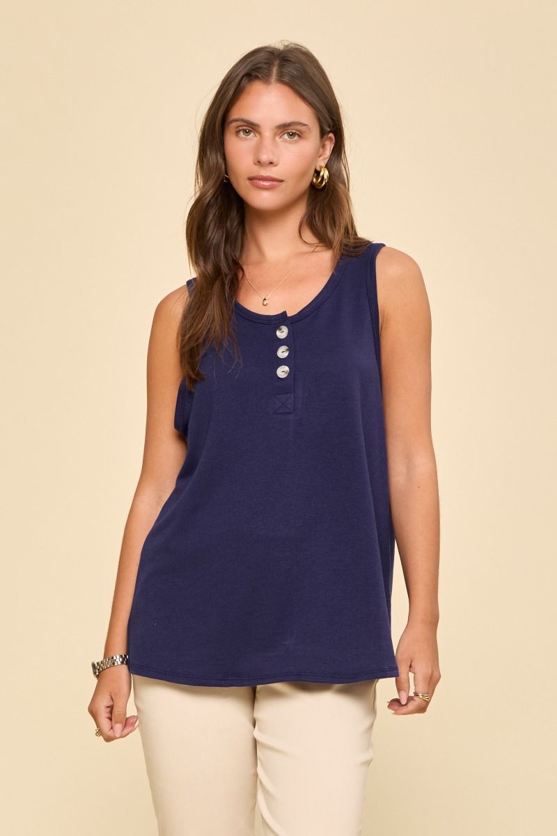 Woman wearing a blue sleeveless top with buttons on a beige background