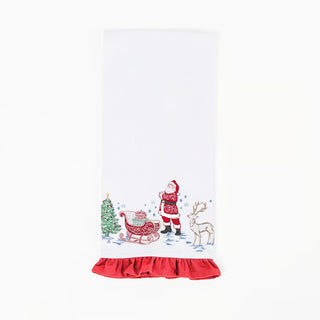 white tea towel with red ruffle trim and  whimsical santa, reindeer, sled, and tree design