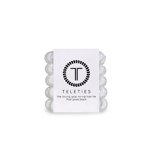 Pack of five white hair ties with the brand logo 'TELETIES' printed on the packaging, labeled as 'Coconut White' and stating 'The strong grips that give back'.