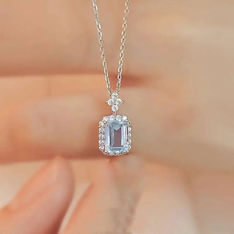 Silver necklace with a pendant featuring a rectangular gemstone on a blurred background