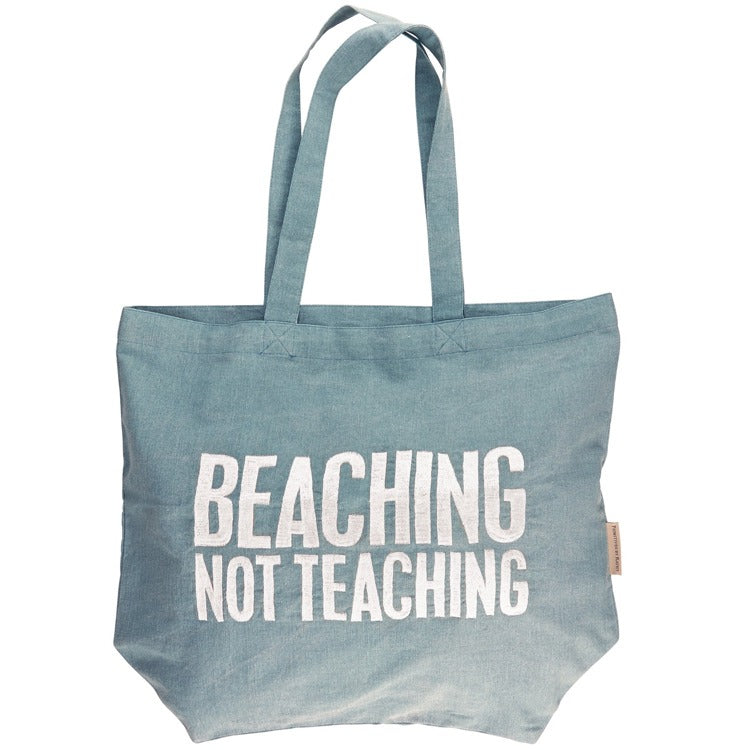 Blue tote bag with 'Beaching Not Teaching' text on a white background