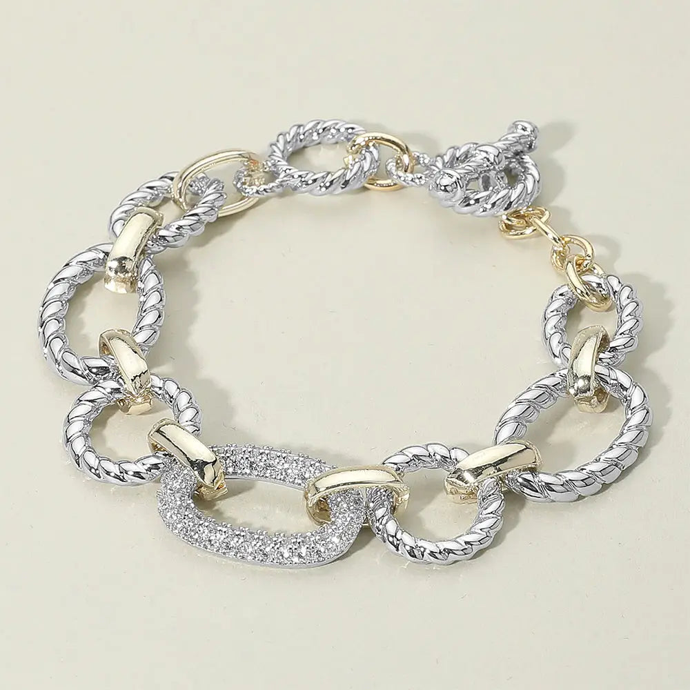 Silver and gold chain bracelet on a light beige background