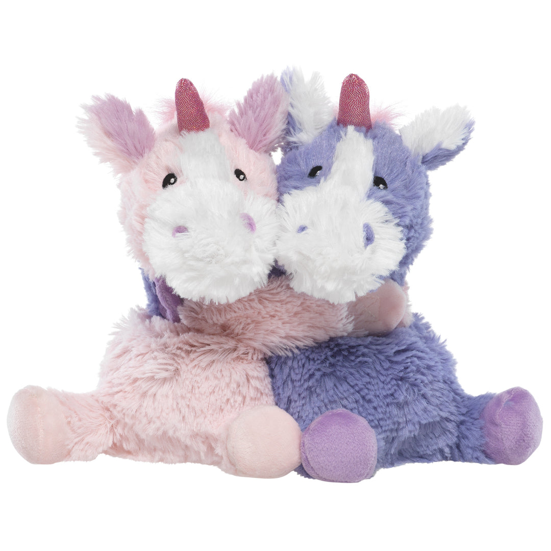 Two plush unicorns, one pink and one purple, sitting together on a white background.