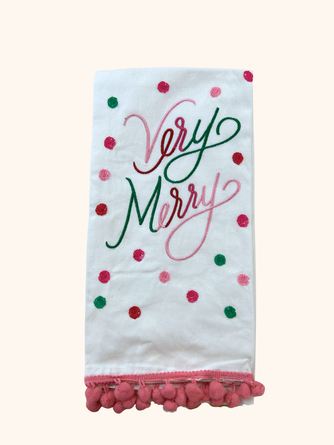 Decorative towel with 'Very Merry' text and pom-pom trim on a white background