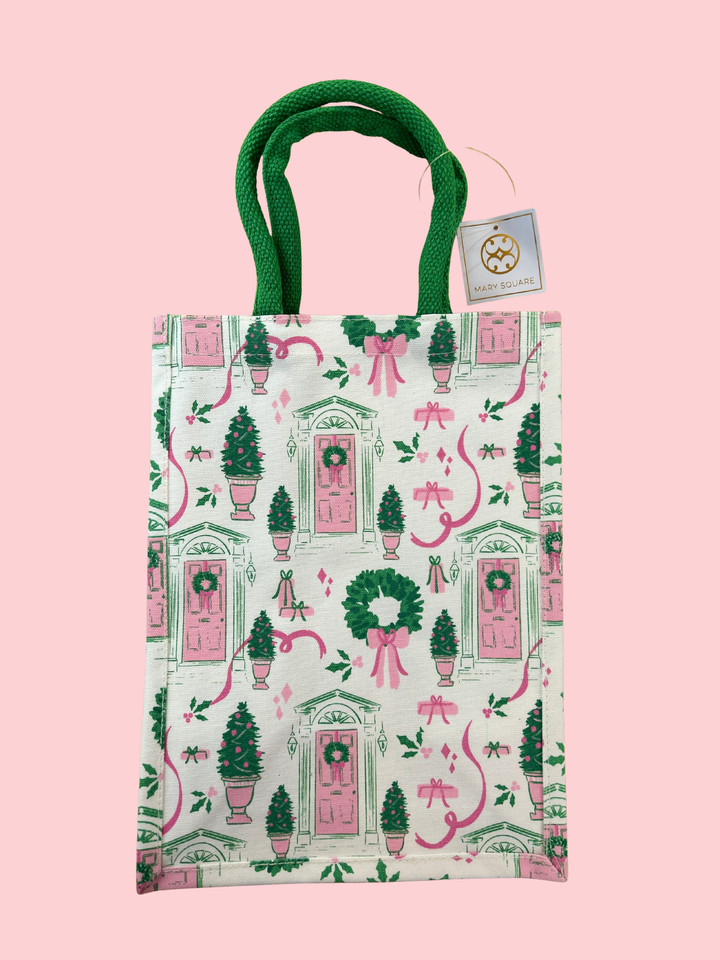Small bag with festive design featuring pink doors, green trees, and red bows on a pink background.