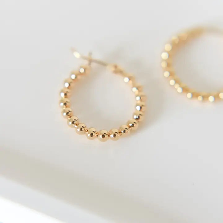 Gold beaded hoop earrings on a white background