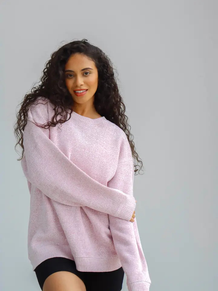 Woman wearing a pink sweater against a plain background