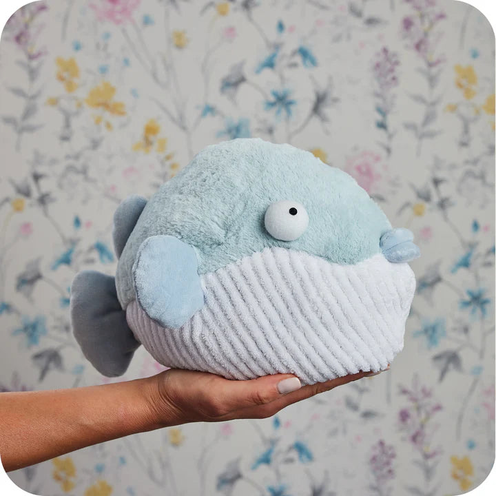 Plush toy whale held by a hand with a floral background