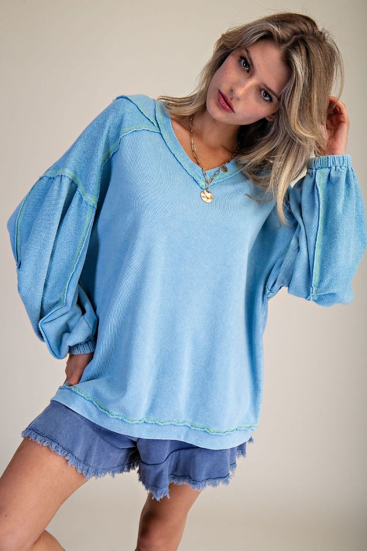 Woman wearing a light blue oversized sweater and shorts on a plain background