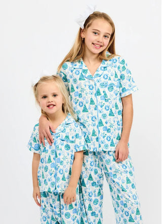 kids wearing white christmas pajamas with green trees, blue gifts, bows, and wreaths design