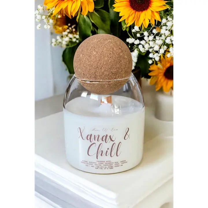 white candle in glass jar with wooden wick and round cork topper