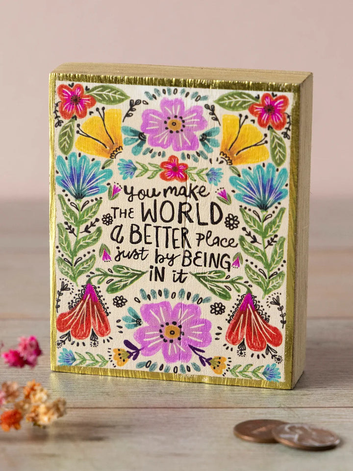 Decorative box with floral design and motivational quote on a wooden surface.