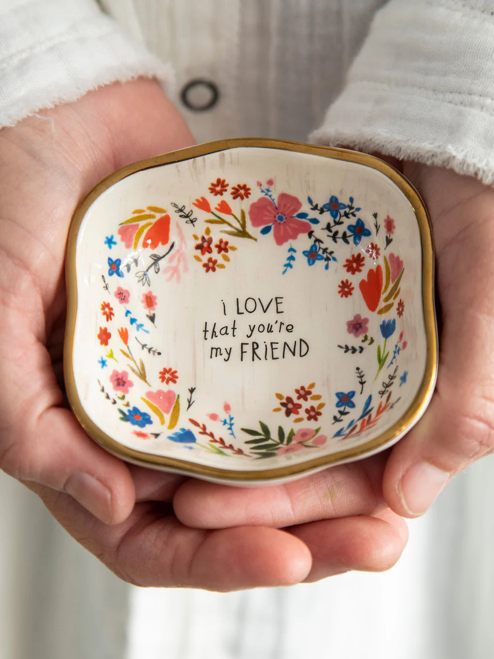 Decorative bowl with floral design and text held in hands
