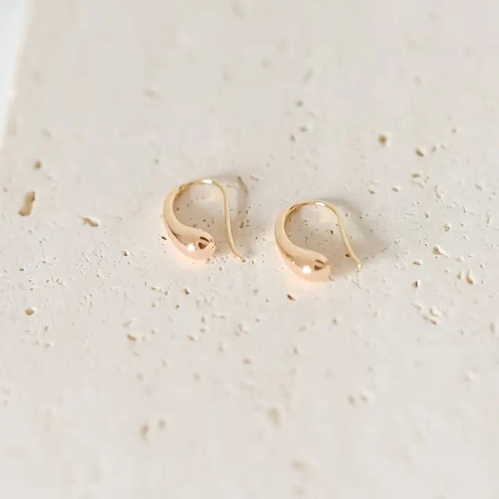 Gold hoop earrings on a textured beige surface