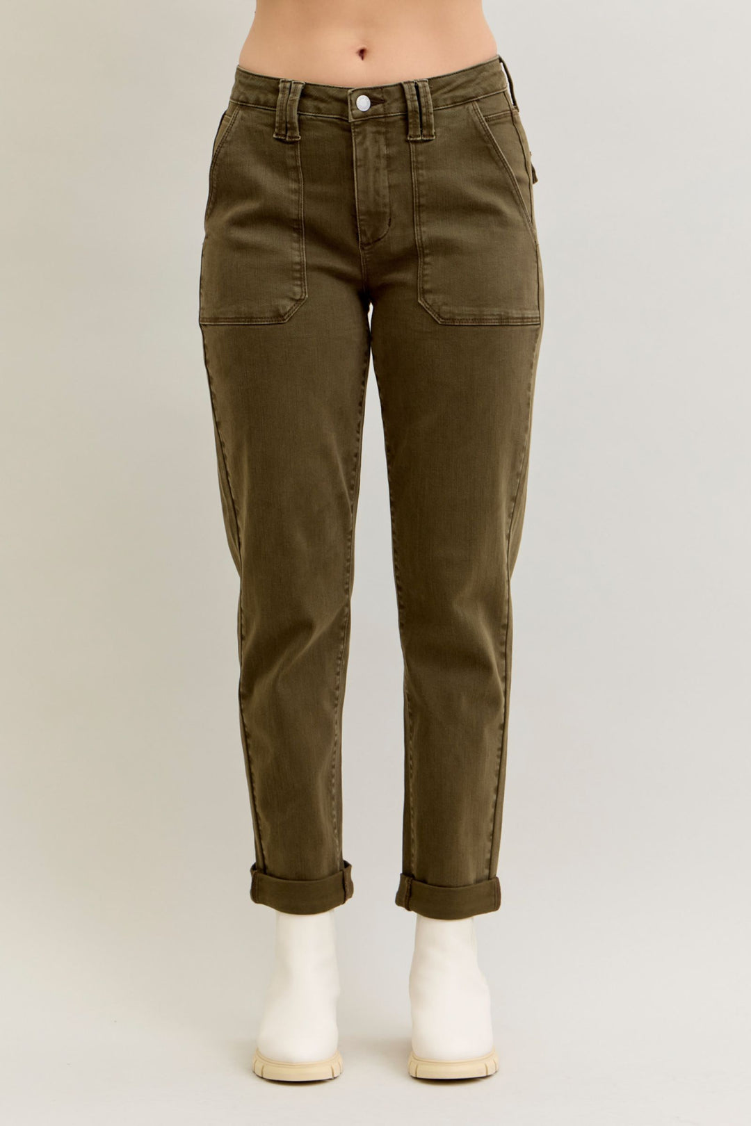 Olive green pants worn by a person on a plain background