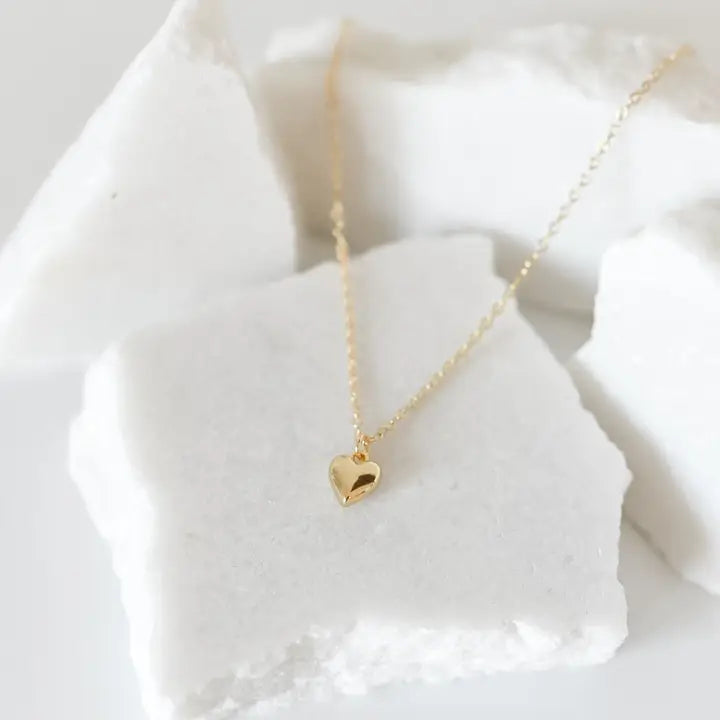 Gold heart-shaped necklace on a white stone surface