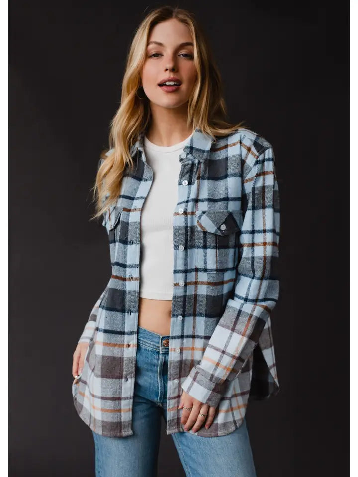 Woman wearing a plaid shirt over a white top and jeans on a black background