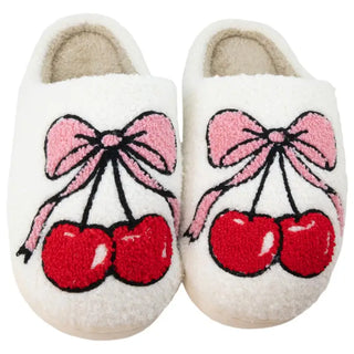 Pair of white slippers with red cherries and pink bows on a white background