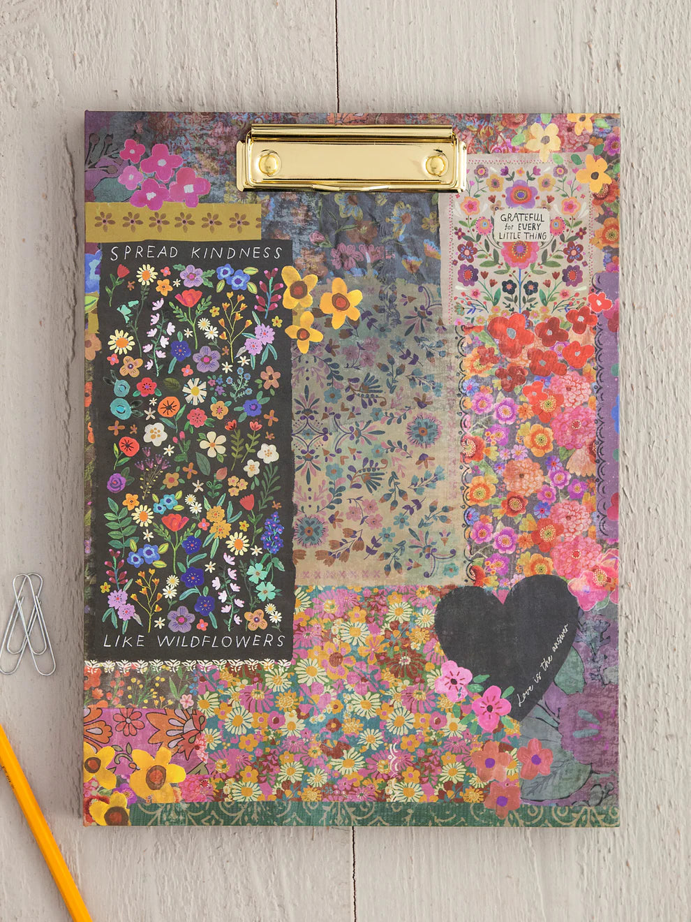 Floral patterned clipboard with motivational text on a wooden surface