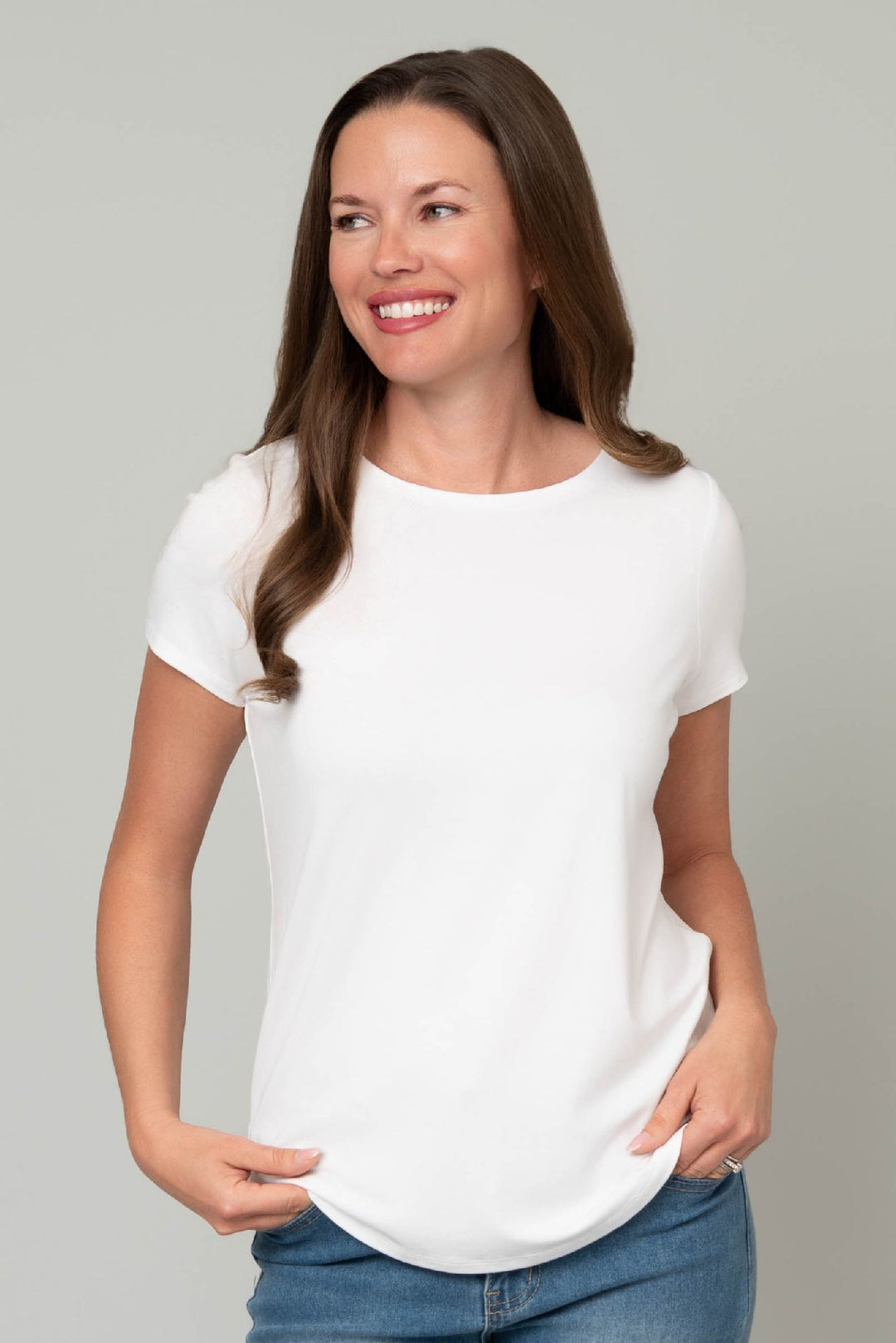 Woman wearing a white t-shirt and blue jeans against a gray background