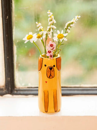 Dog-shaped vase with flowers in front of a window