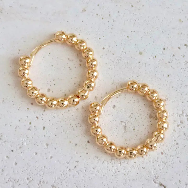 Gold hoop earrings on a light gray surface