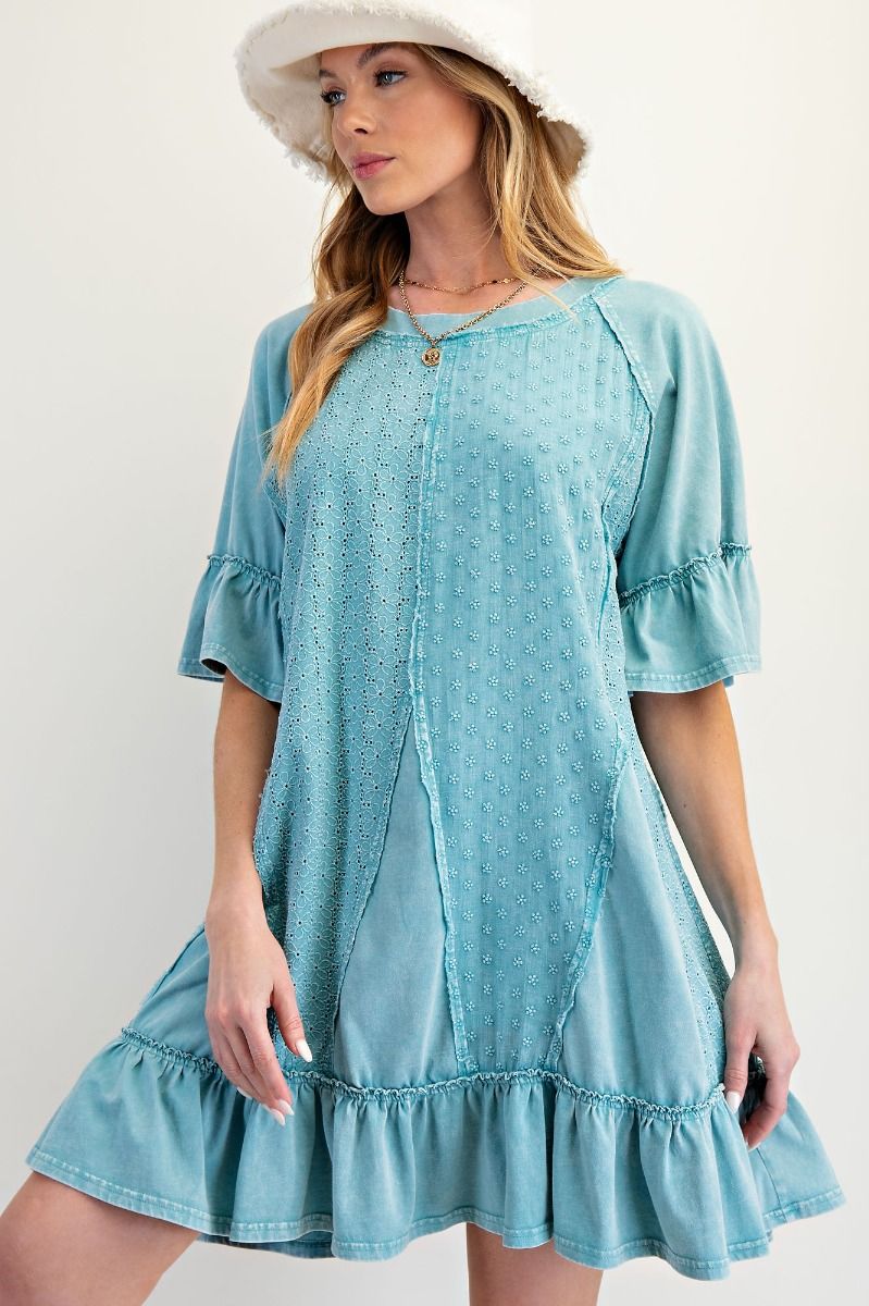a teal cotton mini dress with floral eyelet designs, a ruffled hem, and is a shapeless, oversized fit. 