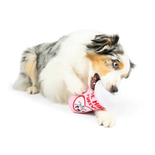 A dog with a double-sided dog toy shaped like a cup, interacting with the toy on a white background.