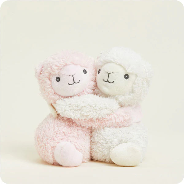 Two pink plush sheep toys sitting together on a white background