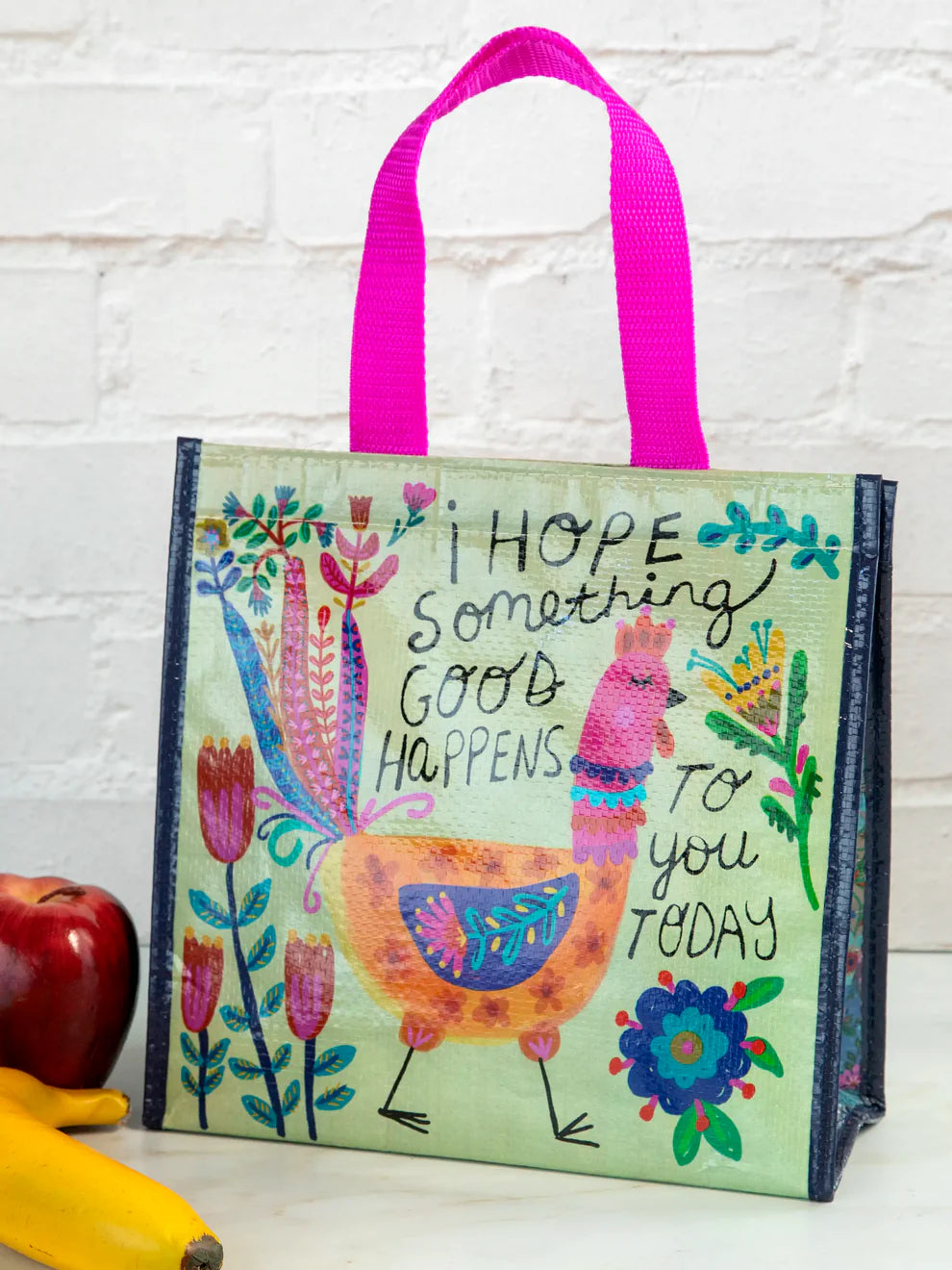 Colorful tote bag with a llama illustration and text on a white brick wall background