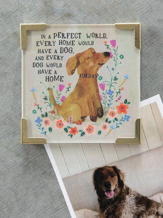 Decorative sign with a dog illustration and text, placed on a surface with a dog lying below.