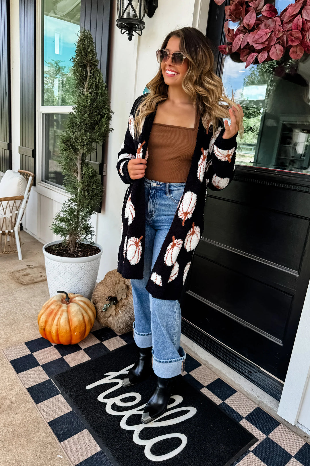 woman in long black cardigan with white and orange pumpkins