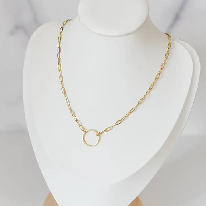 Gold chain necklace on a mannequin bust against a plain background