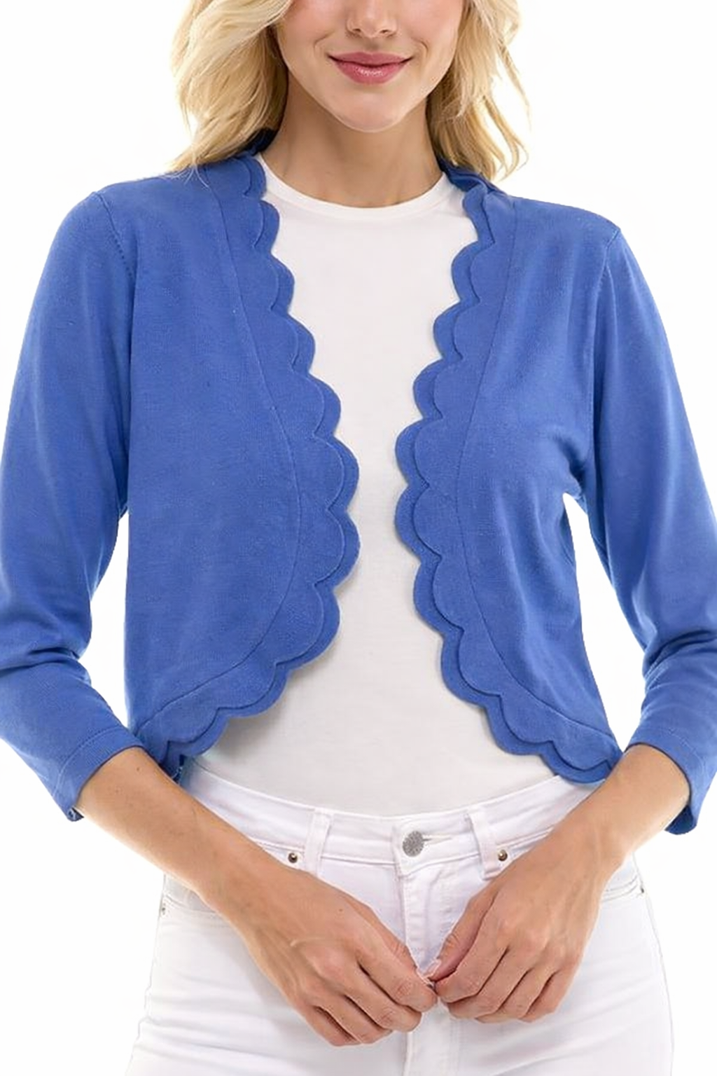 Woman wearing a blue scalloped cardigan over a white shirt and pants on a white background