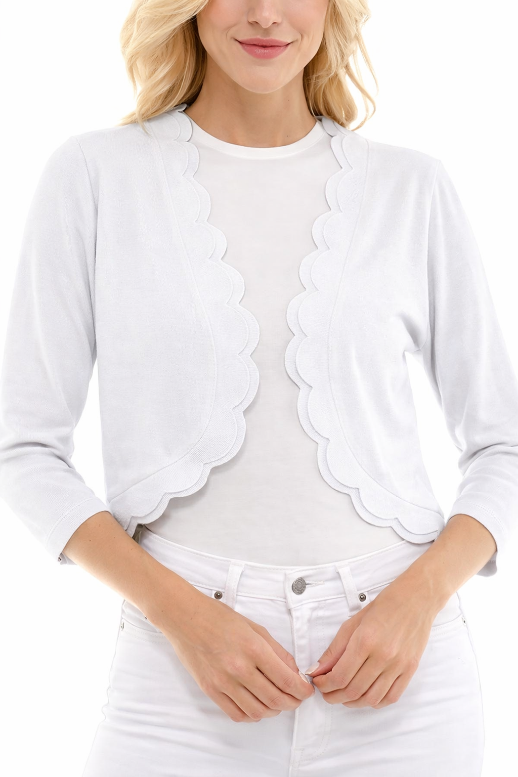 Woman wearing a white scalloped edge cardigan over a white shirt with white pants on a white background