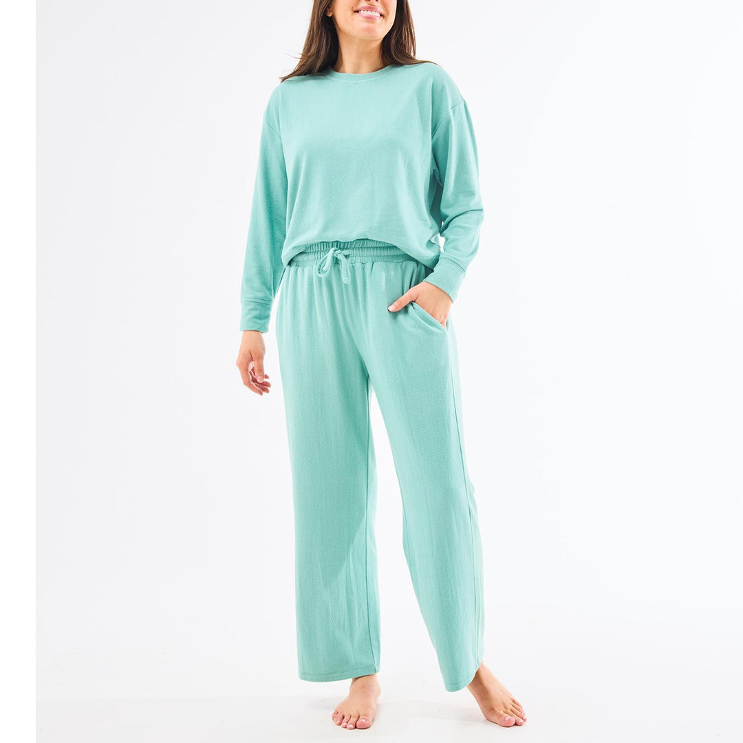 Woman wearing a mint green pajama set on a white background