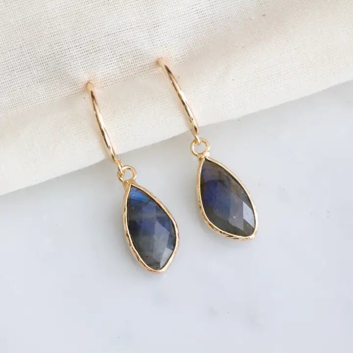 Gold earrings with blue teardrop-shaped stones on a light background