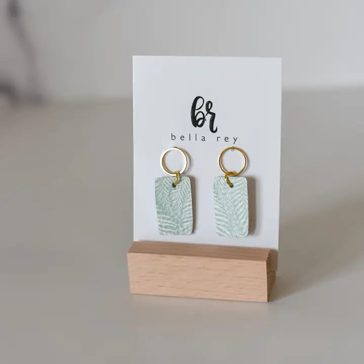 Pair of earrings on a display card with 'bella rey' branding on a neutral background