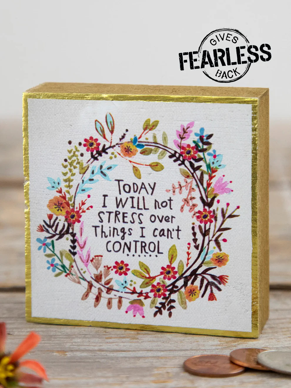 Decorative box with floral design and motivational quote on a wooden surface.